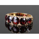 18 carat gold garnet and diamond set ring with a row of five garnets each flanked by diamonds,