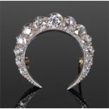 Large white and yellow metal diamond set crescent brooch, with an arched row of thirteen diamonds at