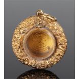 19th Century yellow metal locket with a foliate border and glass central locket, 30mm diameter