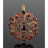 9 carat gold and garnet set pendant brooch, designed with a swirl star design, 33mm diameter