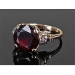 Yellow metal and garnet set ring, the central garnet with white metal shoulders and four claw mount,