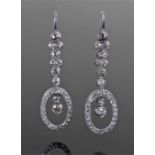 Pair of diamond set drop earrings, the diamond set band with an oval end enclosing two further