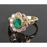 18 carat gold emerald and diamond ring, the central oval cut emerald at 0.64 carat surrounded by