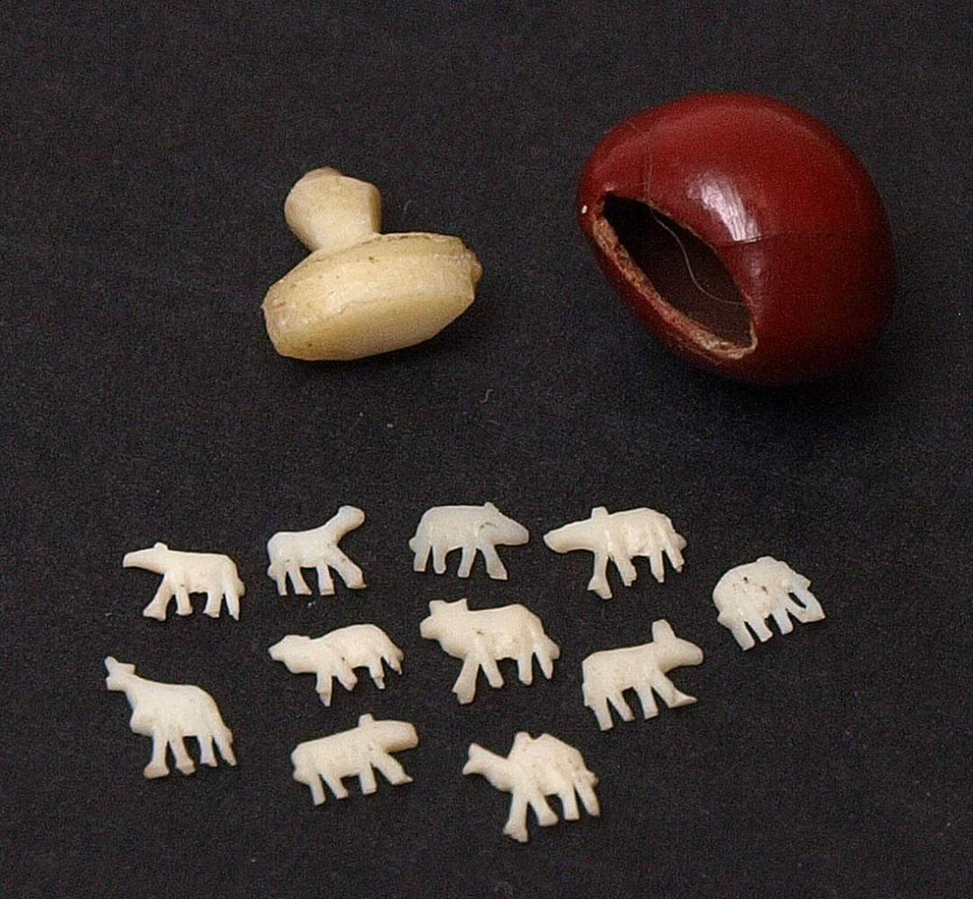 Miniaturschnitzerei, ChinaKorpus aus rot gelacktem Kirschkern mit Elfenbeinstopfen als Deckel. Darin