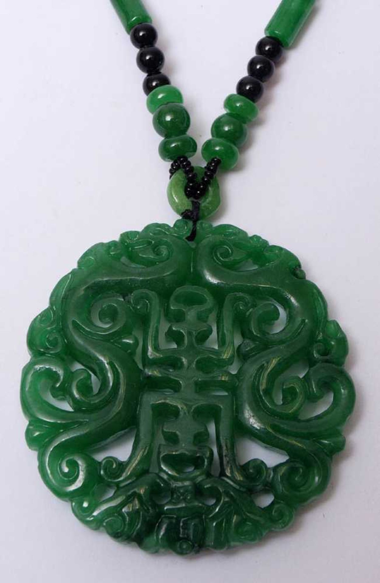 Anhänger, ChinaIn Form eines durchbrochen gesägten Schriftzeichens aus grüner Jade. Dazu passende