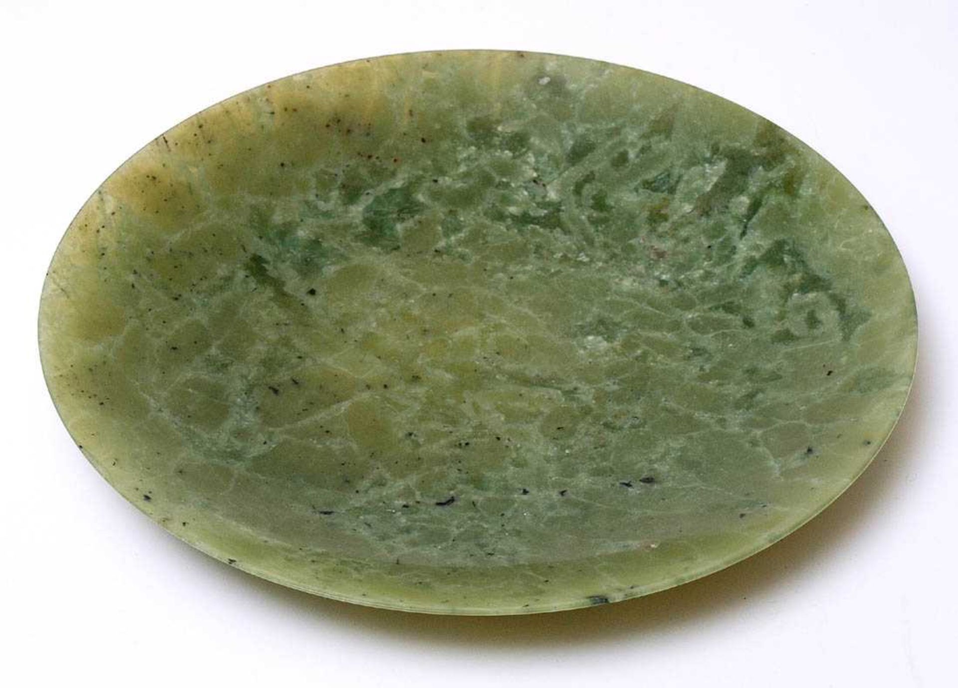 Jadeteller, ChinaFlachgemuldete Form. Hellgrüne Jade mit dunklen Tupfen und Quarzadern. Durchm.9,