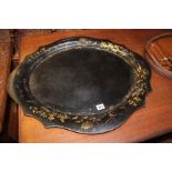 A Victorian ebonised and gilt decorated tray and another oval example depicting a harbour scene