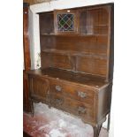 A late Victorian oak dresser with a platerack and cupboard and drawers below on cabriole legs