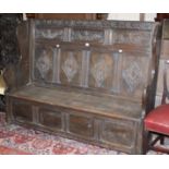 A Victorian style oak settle with lozenge carved panelled back and hinged seat 153cm length