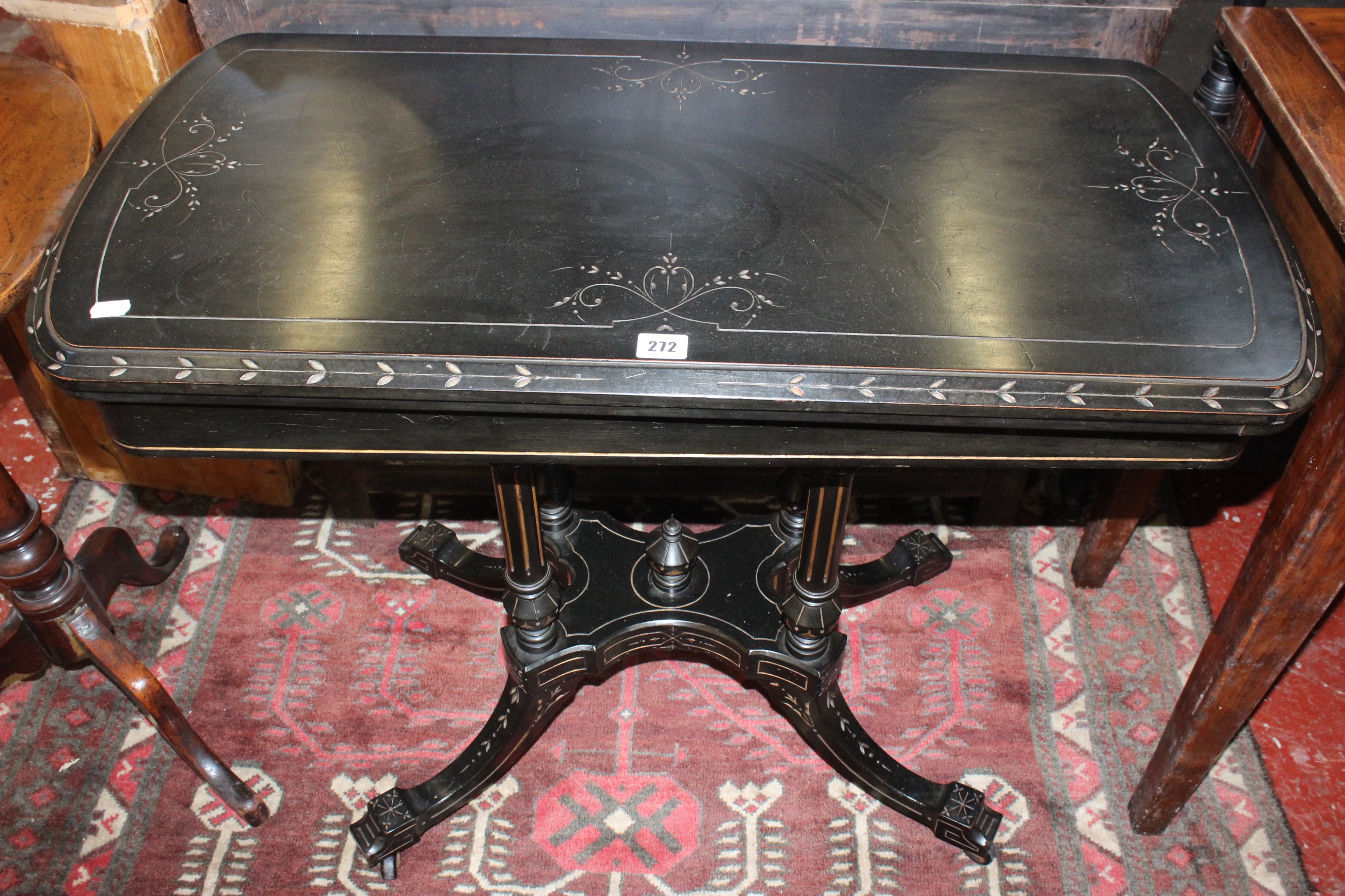A Victorian ebonised card table with four column supports on splayed legs 90cm wide