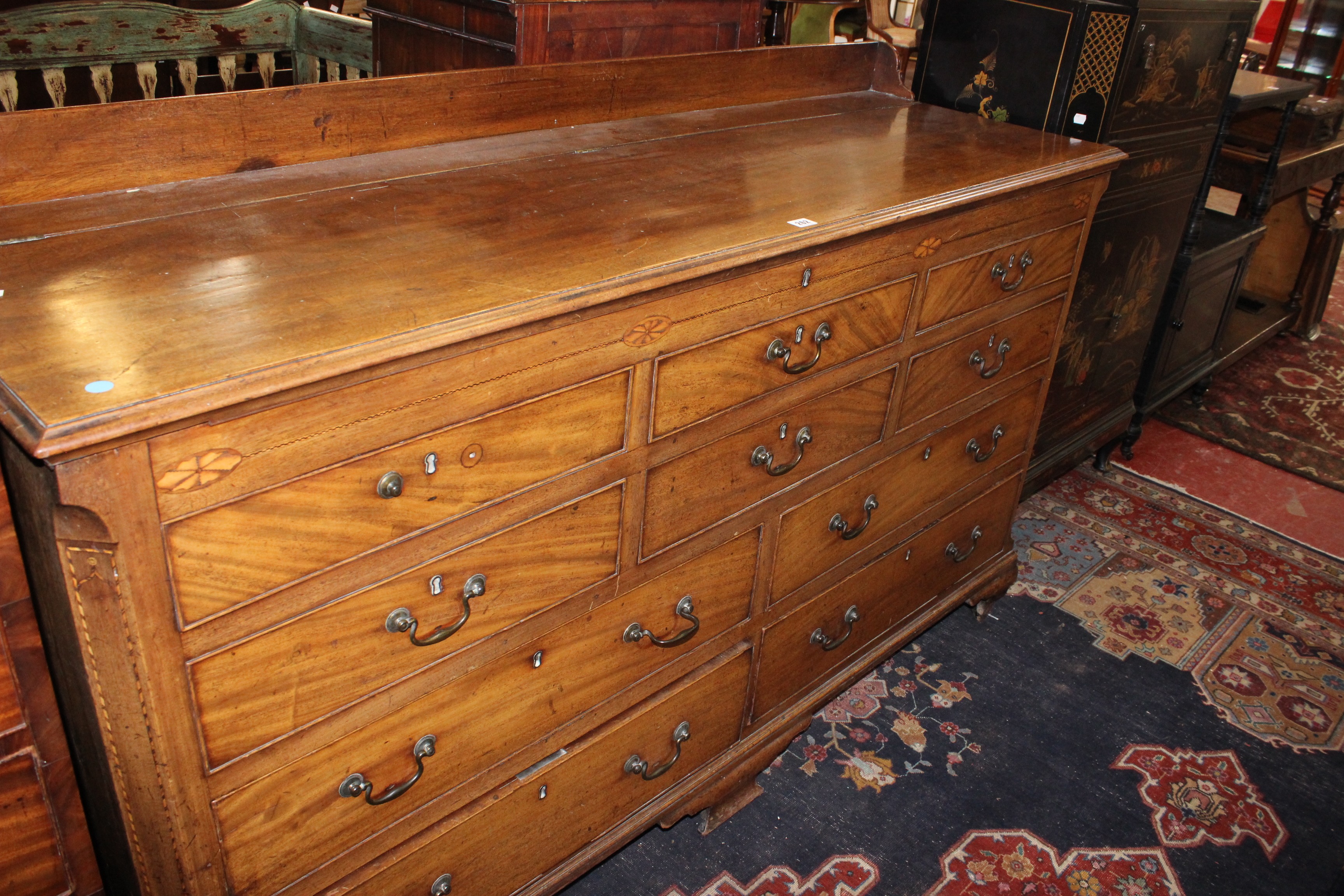 A George III mahogany and inlaid mule chest with a hinged lid, with four long drawers on bracket