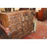 An Indian carved hardwood cupboard with carved panelled front on wheels 130cm wide