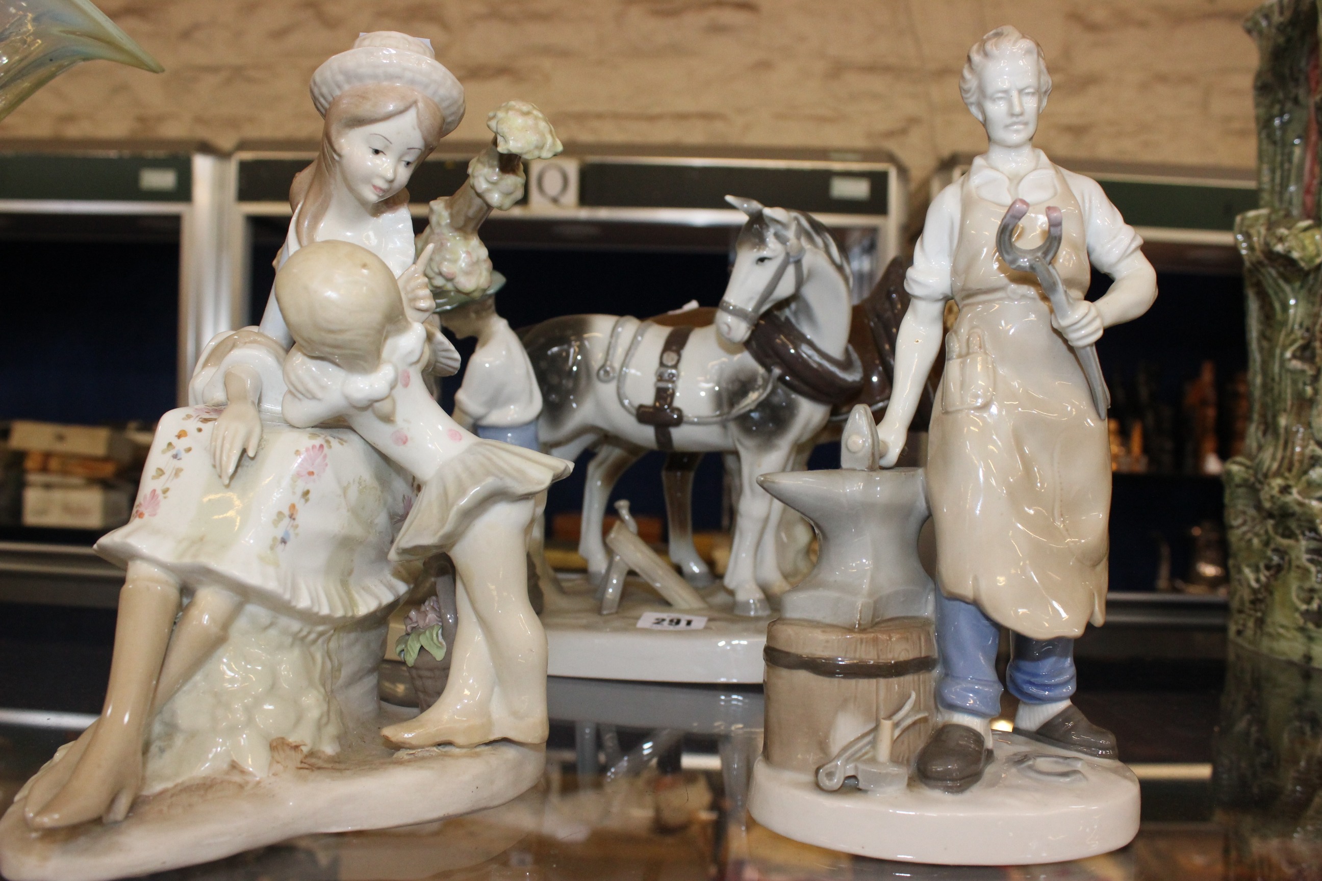 Three Spanish style figurines, the blacksmith and a young girl with child