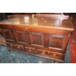An 18th Century style oak mule chest with a hinged lid, fielded panel front and drawers on bracket