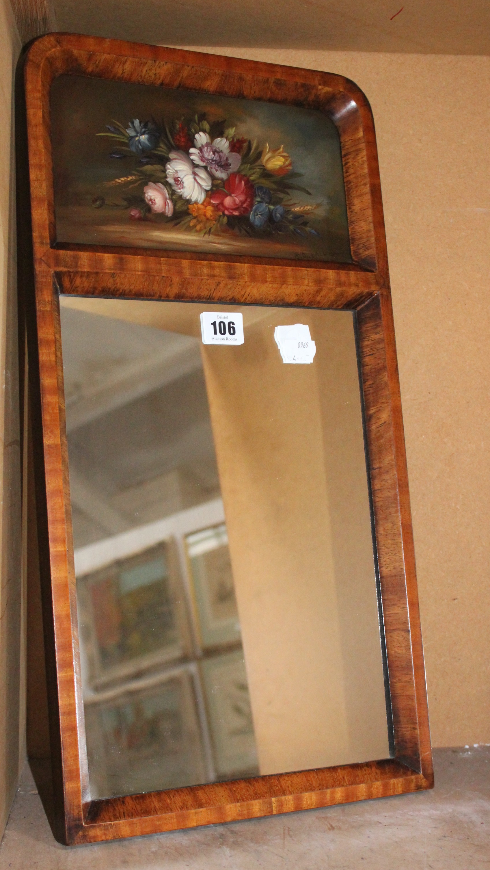 A pair of wooden framed mirrors, each with painted panel, still life of flowers, signed E.M. Ball