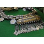 An Omani wedding necklace, the large ornate metal and fabric chain set with eight coins