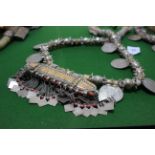 An Omani wedding necklace, the large ornate metal and fabric chain set with eight coins