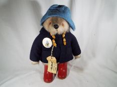 Paddington Bear - a stuffed toy, with pale blue felt hat, dark blue coat and red boots,