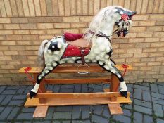 A Rocking Horse by Collingwood finished in dapple grey with a hair mane, stained wood trestle base,