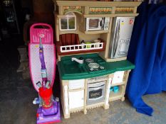 A child's play kitchen with accessories and a child's Dyson vacuum cleaner and ironing board