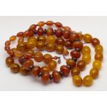 A row of oval Baltic amber beads and a darker graduated row of amber beads with silver spacers.