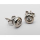 Pair of 9ct white gold diamond ear studs, in a circular rub over setting.