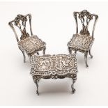 Miniature silver novelty table and chairs in the rococo style, hallmarked.