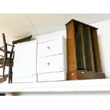 One white bedside chest and one bedside cupboard and a dark wood effect cd rack