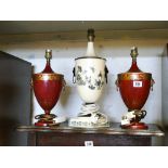 A pair of red lacquered table lamps and a white floral and butterfly decorated table lamp