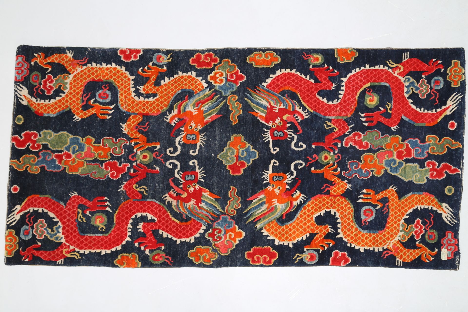 Arte Himalayana. A wooden carpet depicting four dragons chasing the flaming pearl over a blue