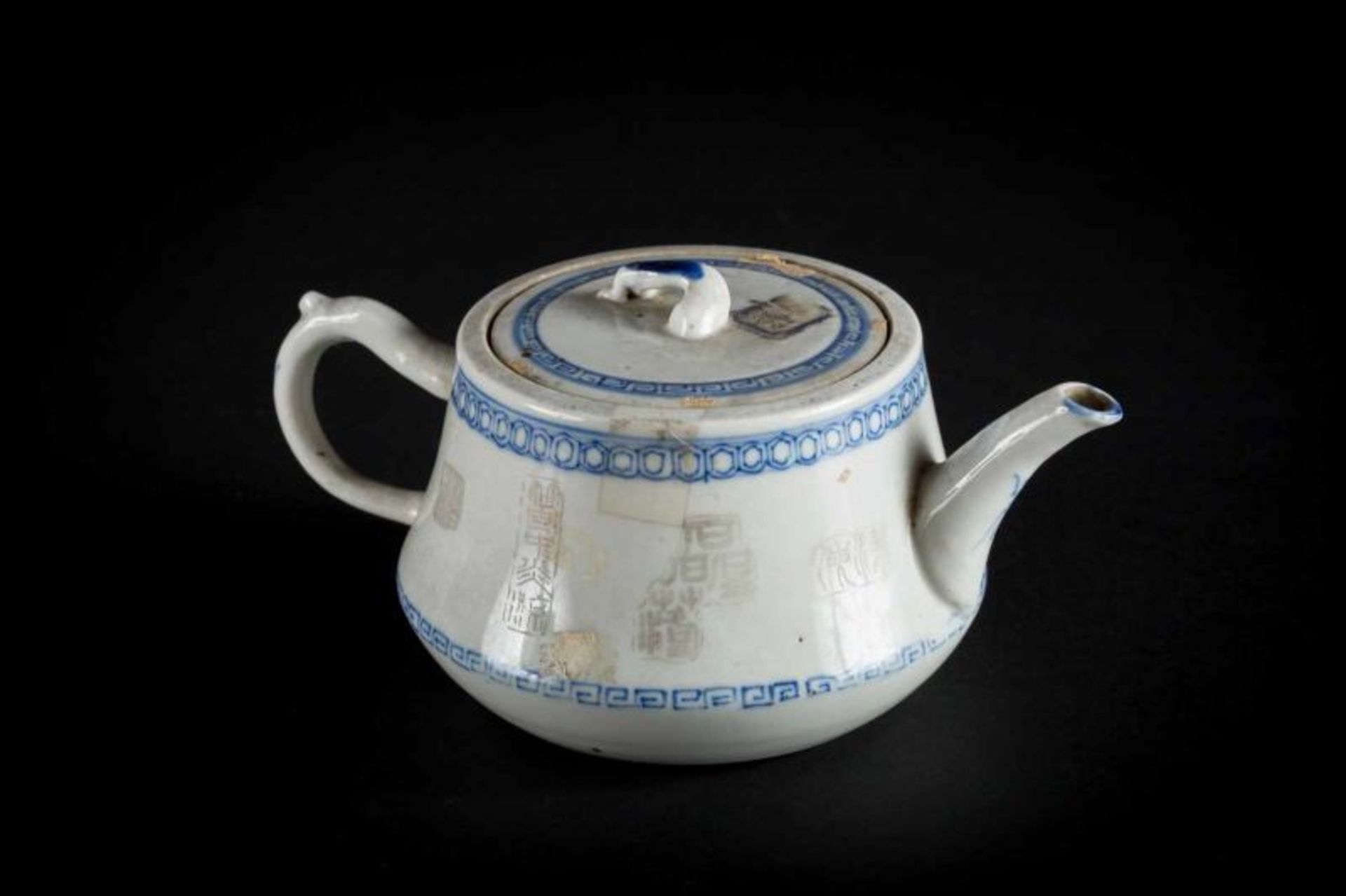 A blue and white porcelain teapot and cover decorated with iron red underglaze stamps and a