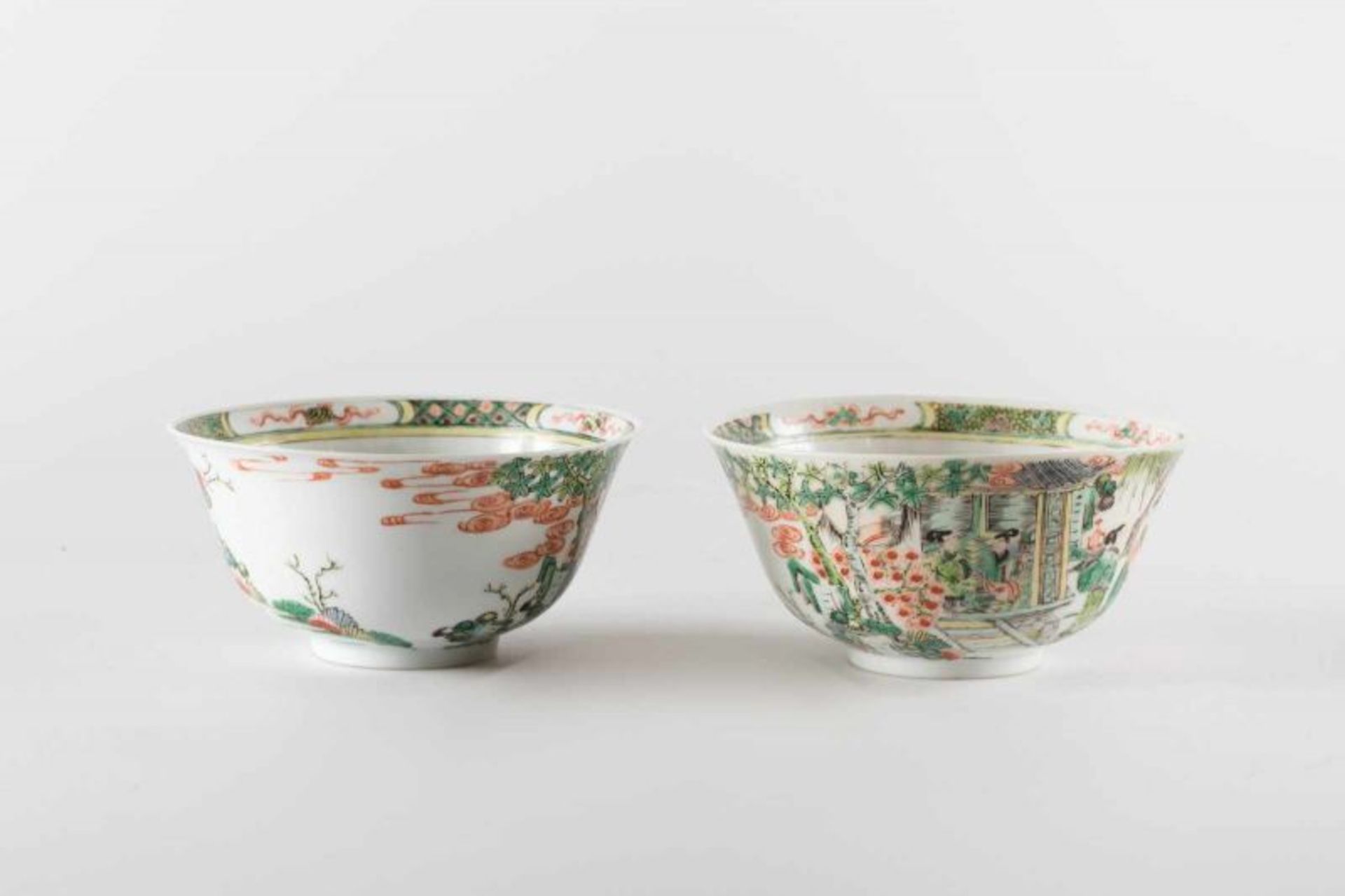 A pair of porcelain famille verte cups painted with ladies in the garden and bearing a red