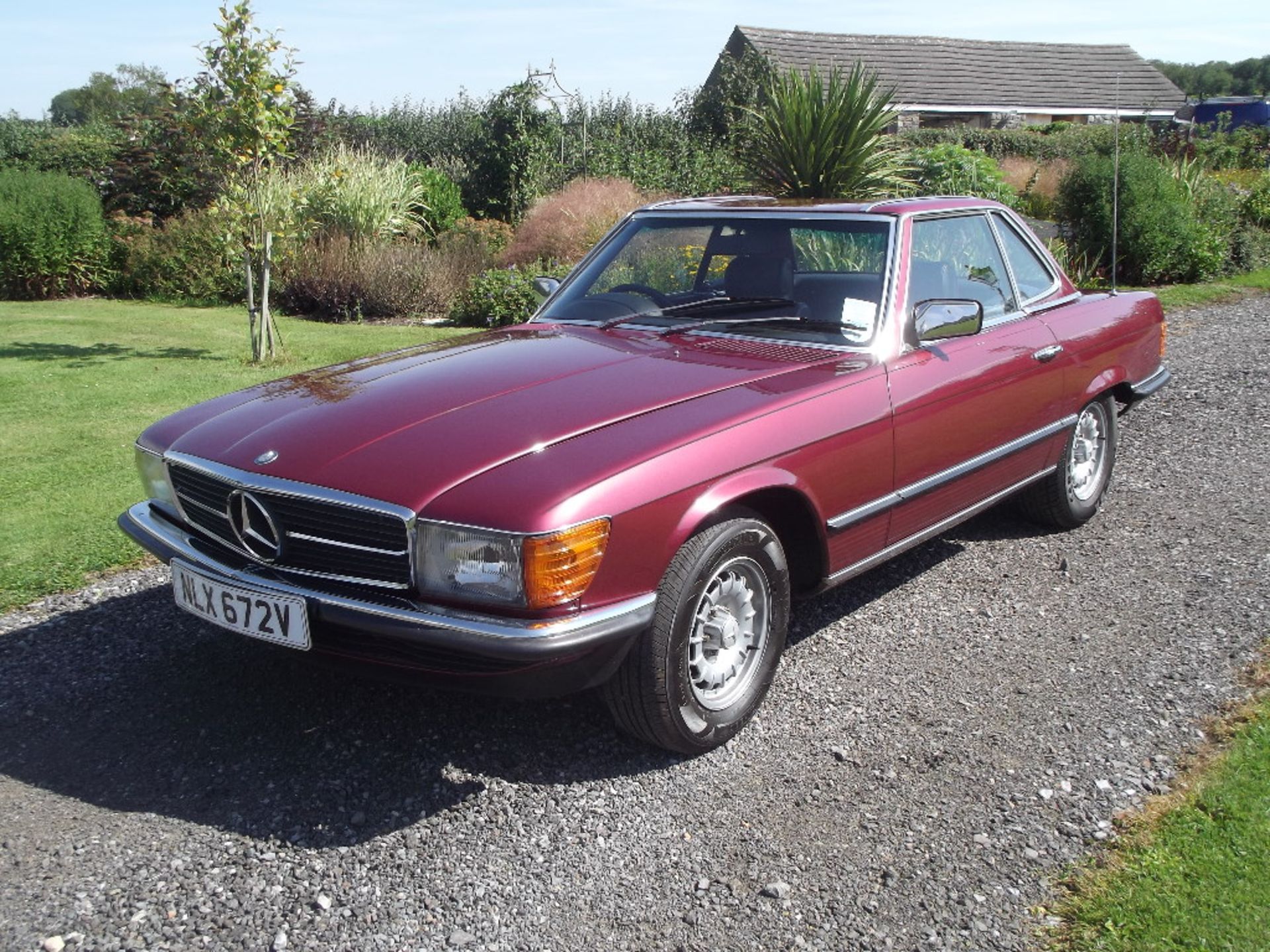 A 1980 Mercedes-Benz 350SL, registration number NLX 672V, metallic red.