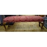 An upholstered footstool, on mahogany cabriole legs,