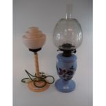 A light blue glass table oil lamp, with painted floral decoration and an etched shade, 58 cm high,