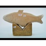 A carved stone fish, on a ham stone plinth, 28.