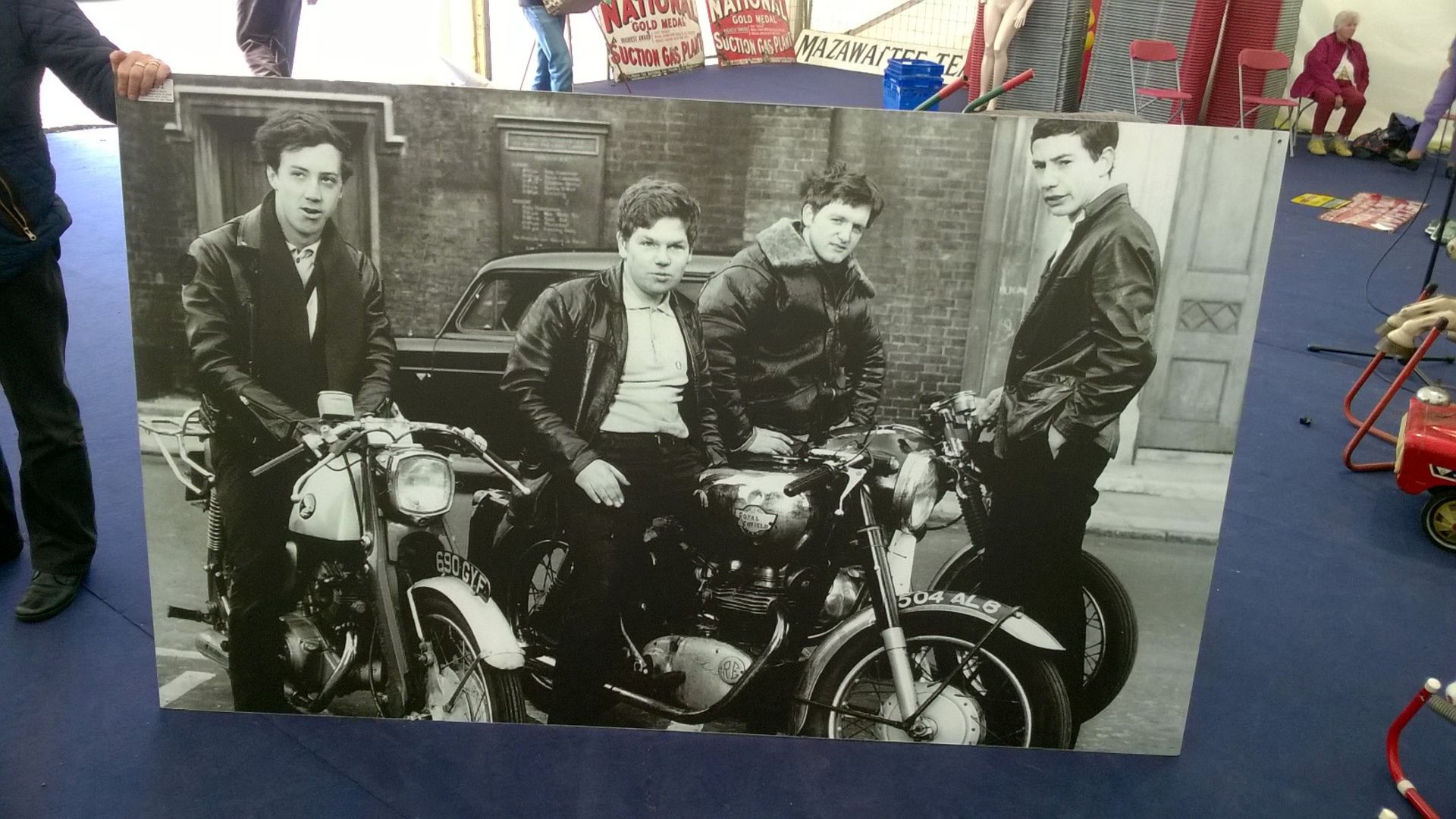 Large black & white print depicting a group of youths with their motorbikes in the 1960s