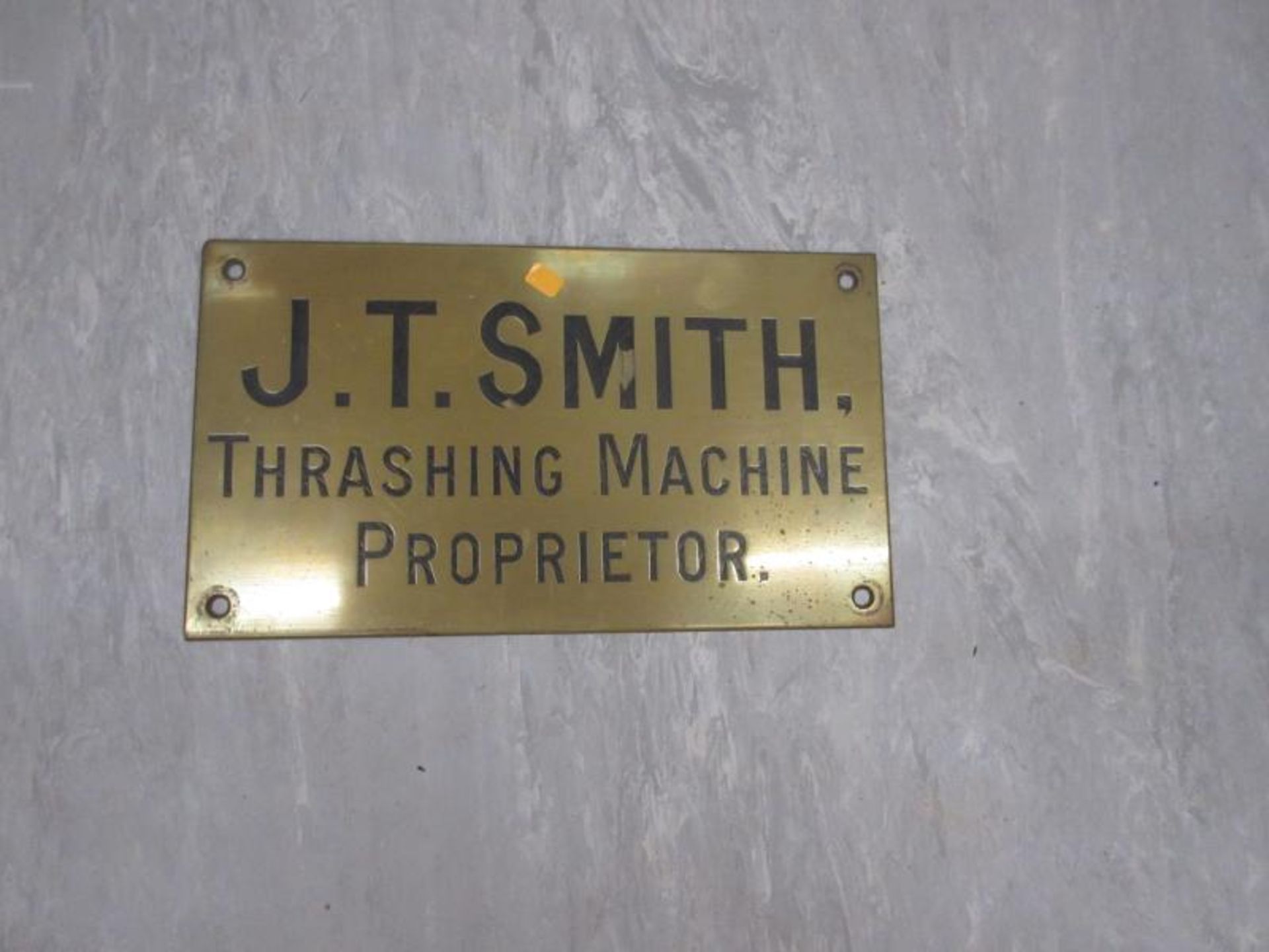 A brass plaque J T Smith Thrashing Machine Proprietor