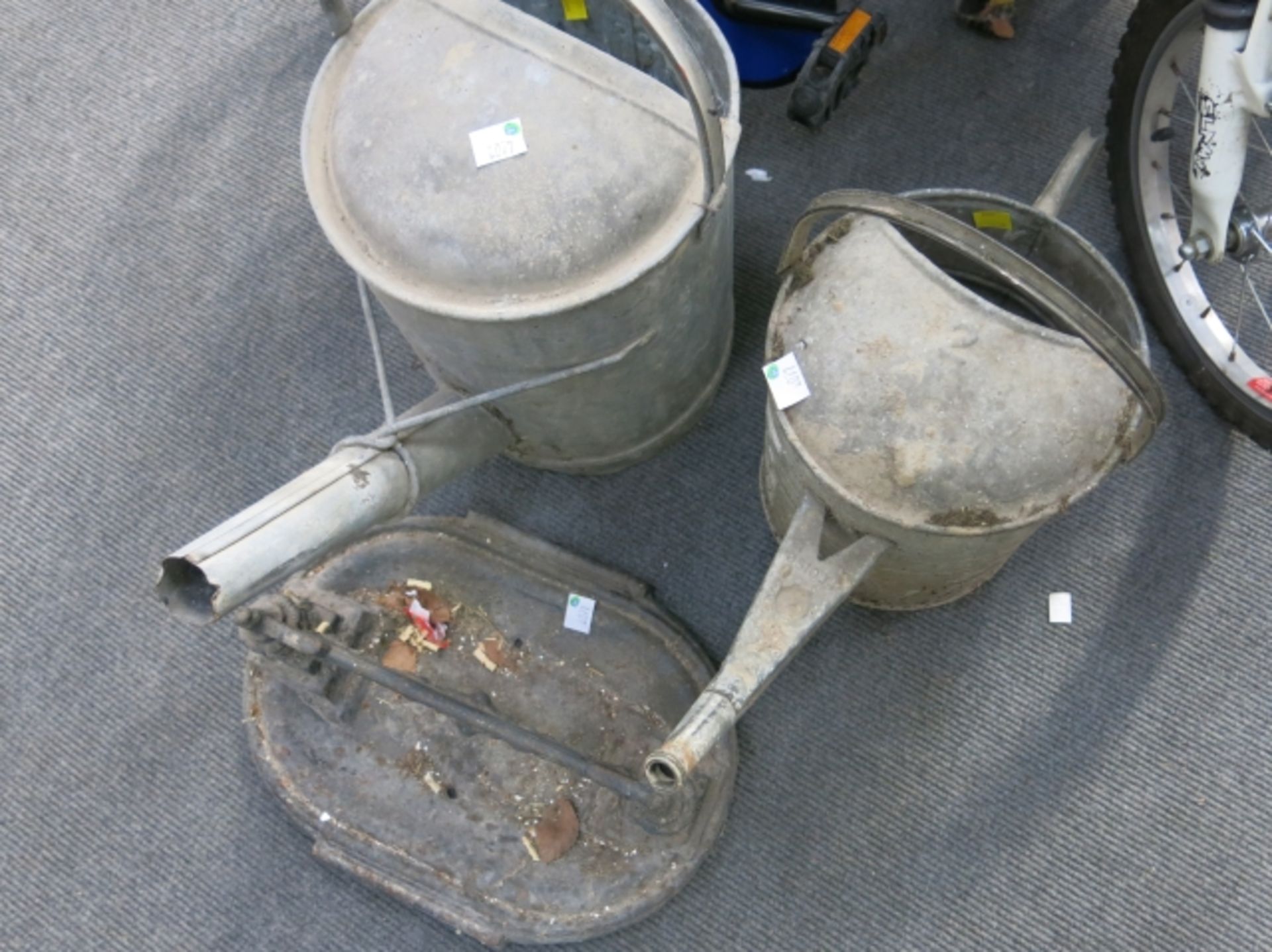 Two galvanised watering cans and a cast iron boot scraper (3) (est £20-£30)