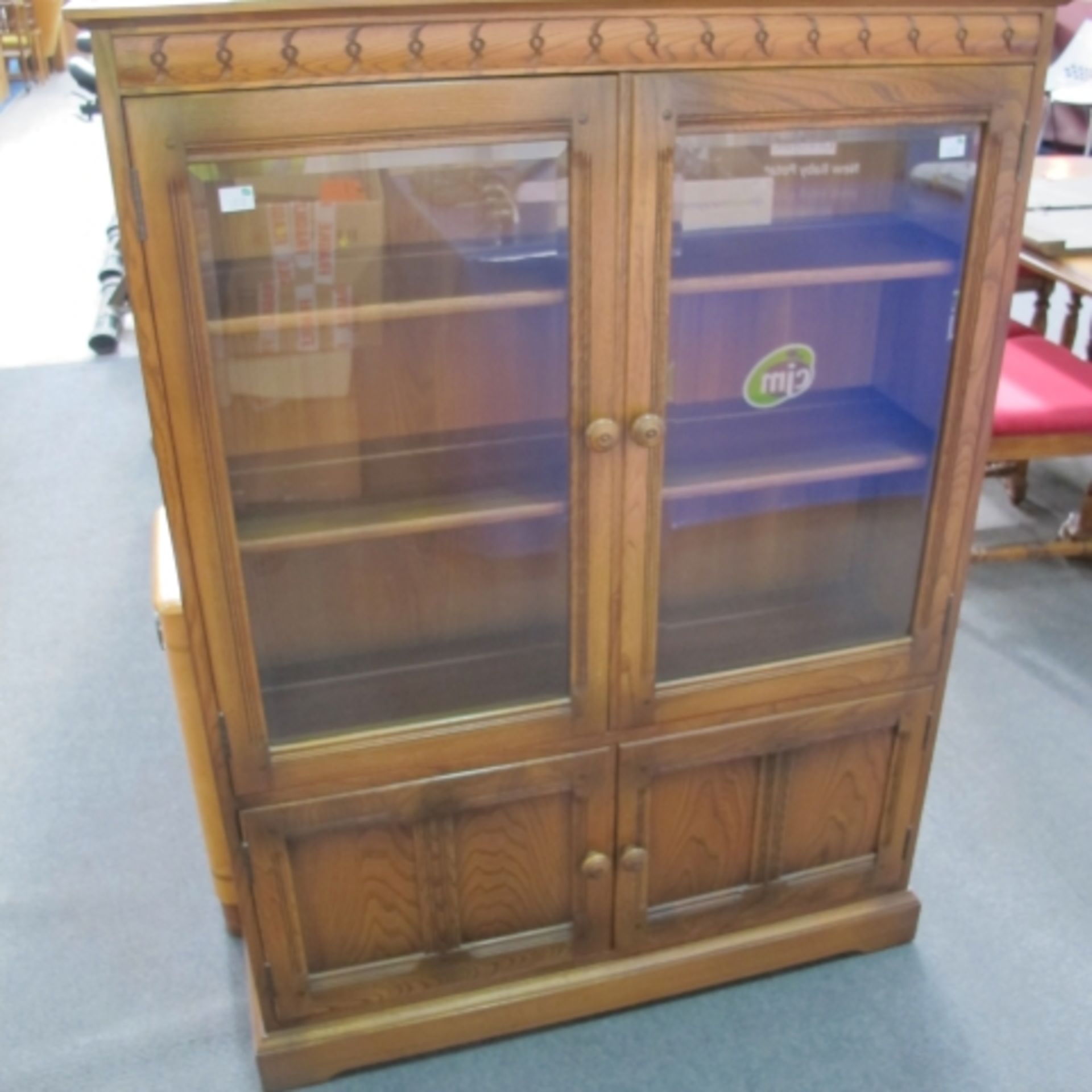 A large reproduction china cabinet with three shelves behind two glazed doors with turn buckle