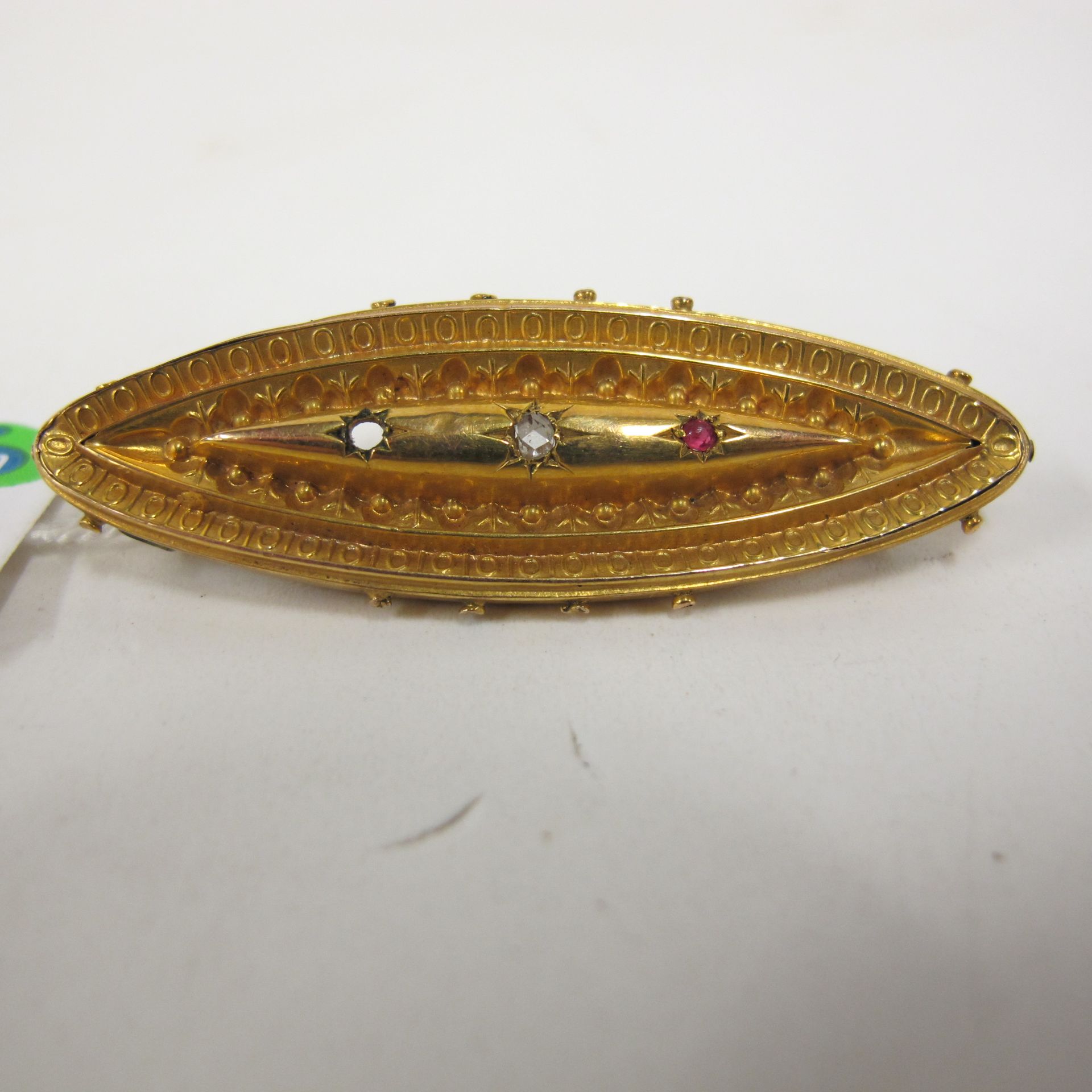 An oval gold brooch set with incomplete set of precious stones, together with another double bar