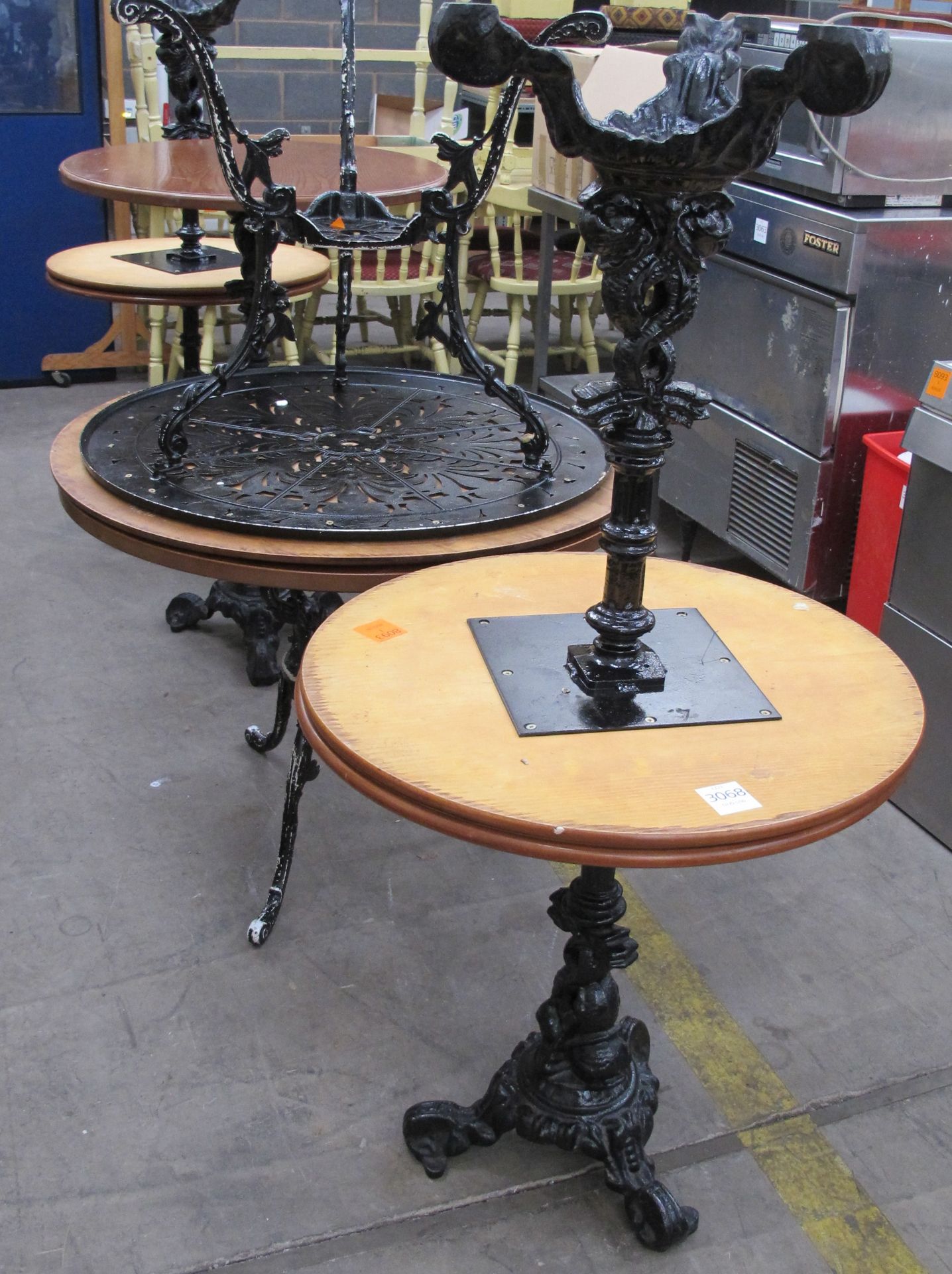 * 7 x various wood and cast iron circular cafe tables. Please note there is a £5 + VAT Lift Out