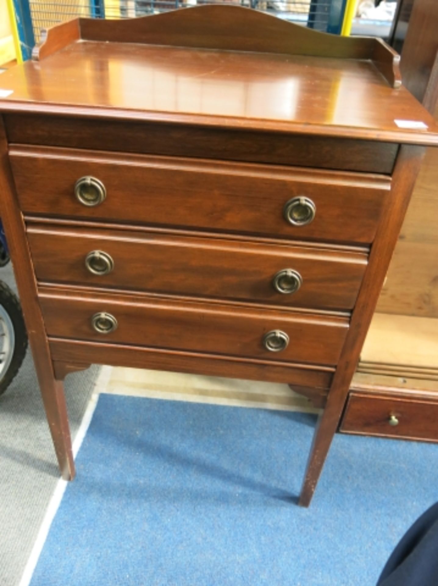 A mahogany three drawer unit with metal circular handles, the top and bottom drawers have drop