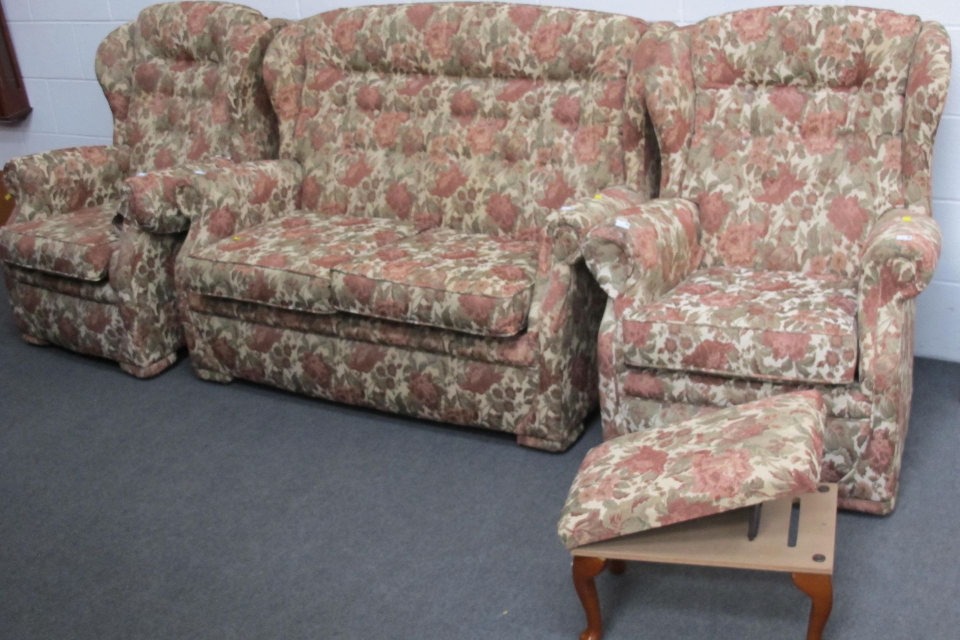 A fabric covered three piece suite - a two seat settee & two wing back armchairs all with floral