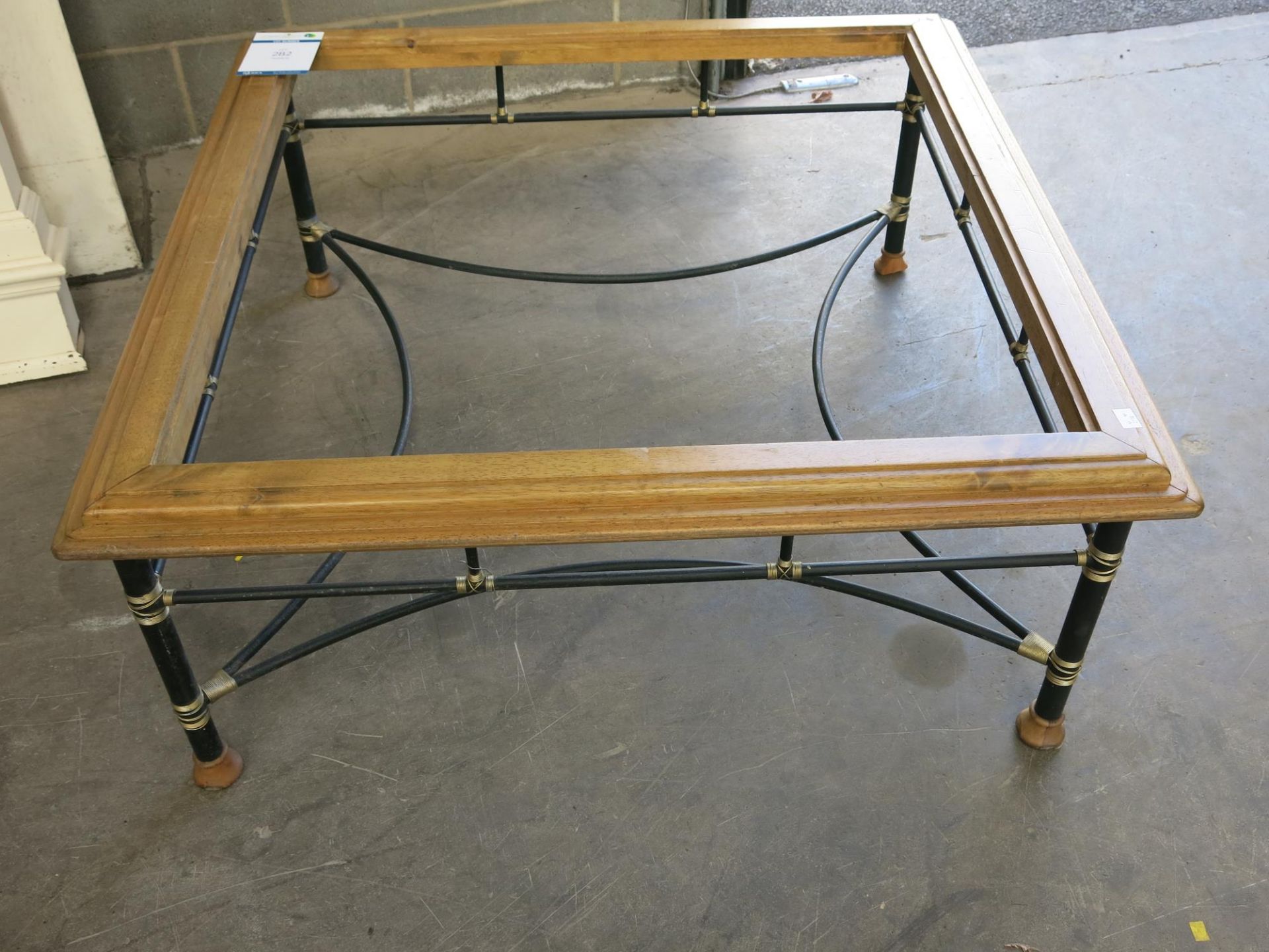 A large wooden coffee table with matt black, round framework with 'Gold' wire supports on turned