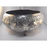 An Indian white metal bowl decorated animals and foliage standing on three twin fish legs (Approx