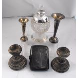 A pair of silver dwarf candlesticks, a silver cigarette case, a silver topped cut glass scent bottle