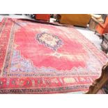 A large Persian floor carpet decorated stylised flowers on a red ground 354cm x 453cm (wear)