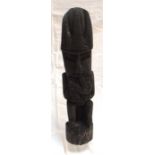 An ethnic carved wooden figure in the form of a seated man wearing a tall hat 47cm high