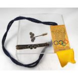 A winter olympics press badge, Lausanne 1986, a silver gilt olympic tie clip and matching tie pin (
